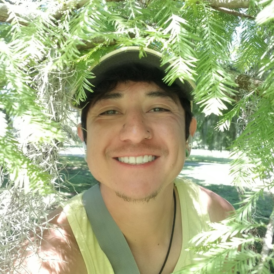 Leo Juarez smiling and surronded by tree branches.
