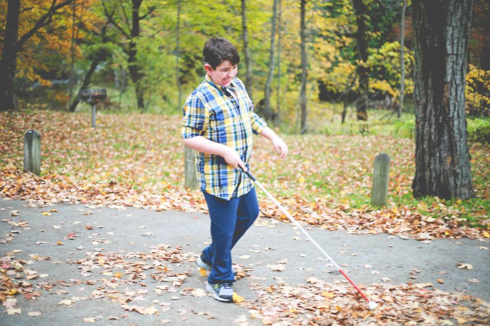 Boy using a cane at the park