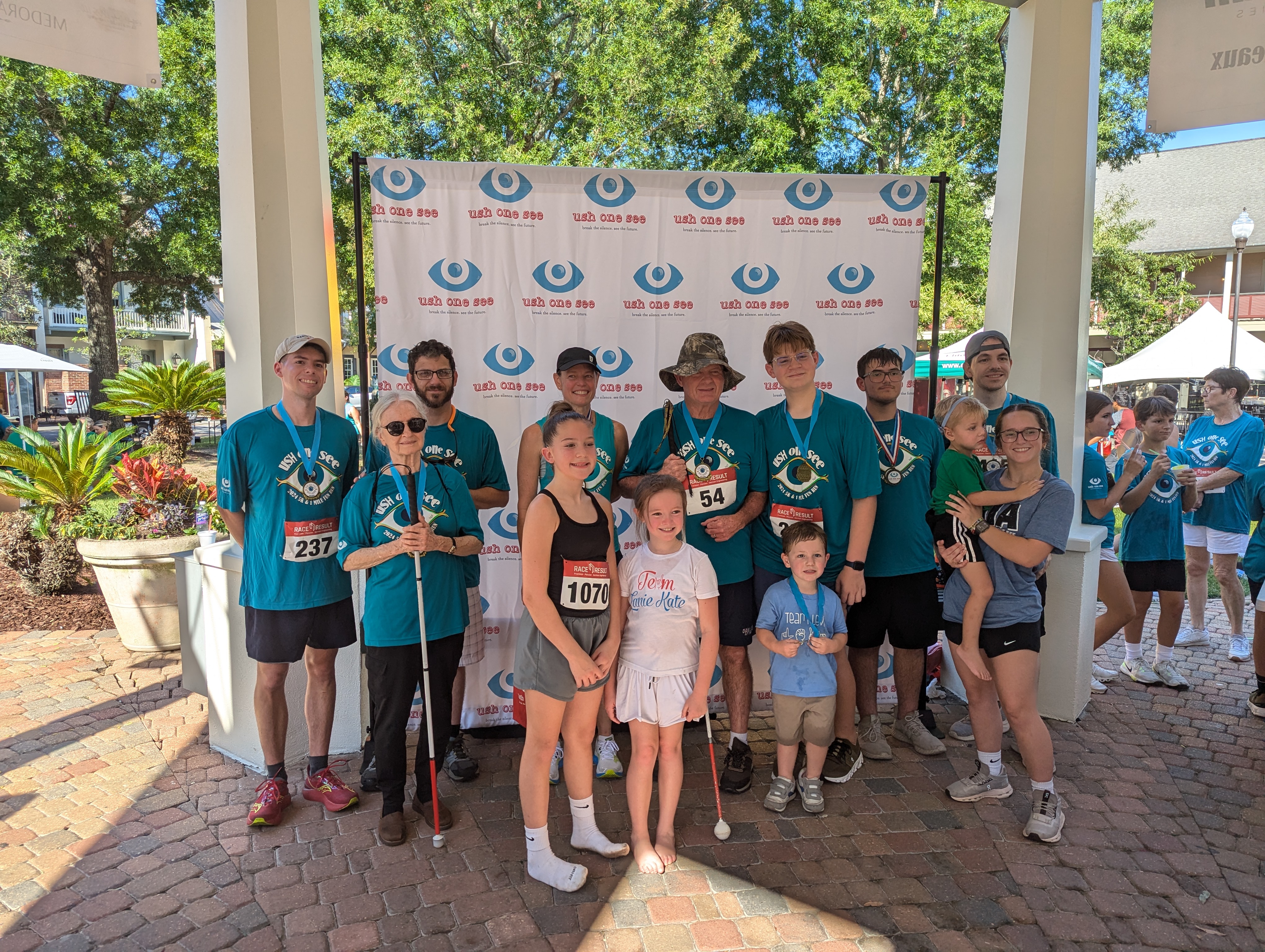 Group of Ush One See runners wearing matching t shirts. Some people hold white canes.