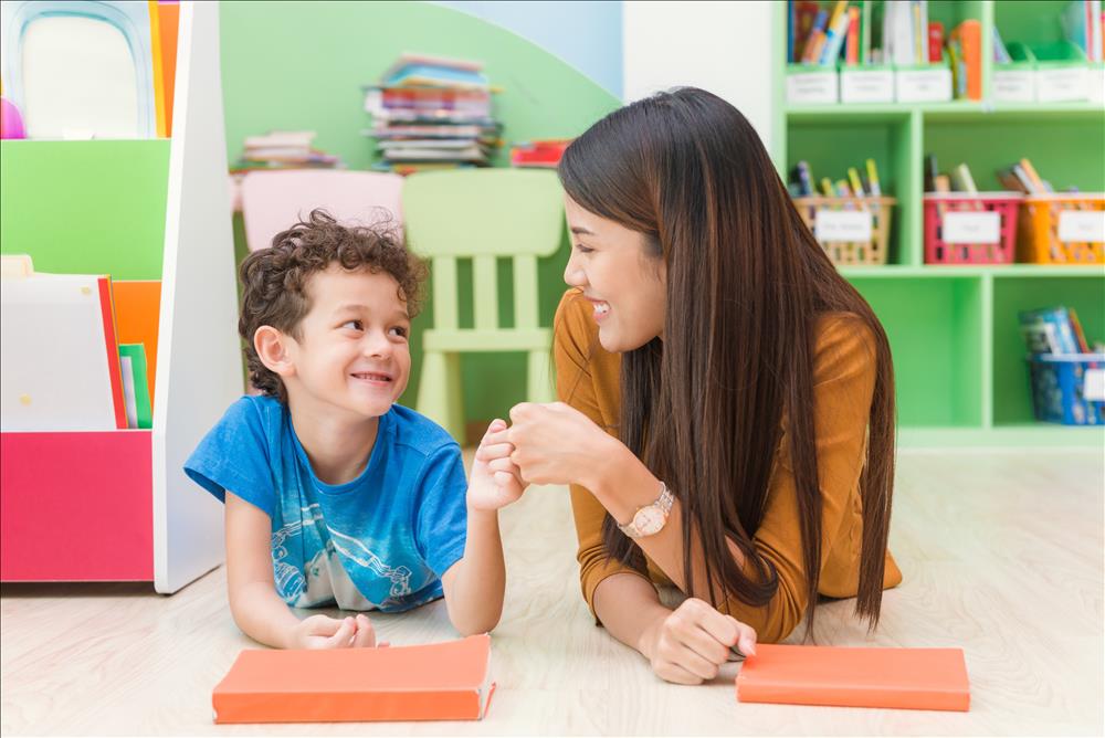 Asian teacher giving mixed race child daps