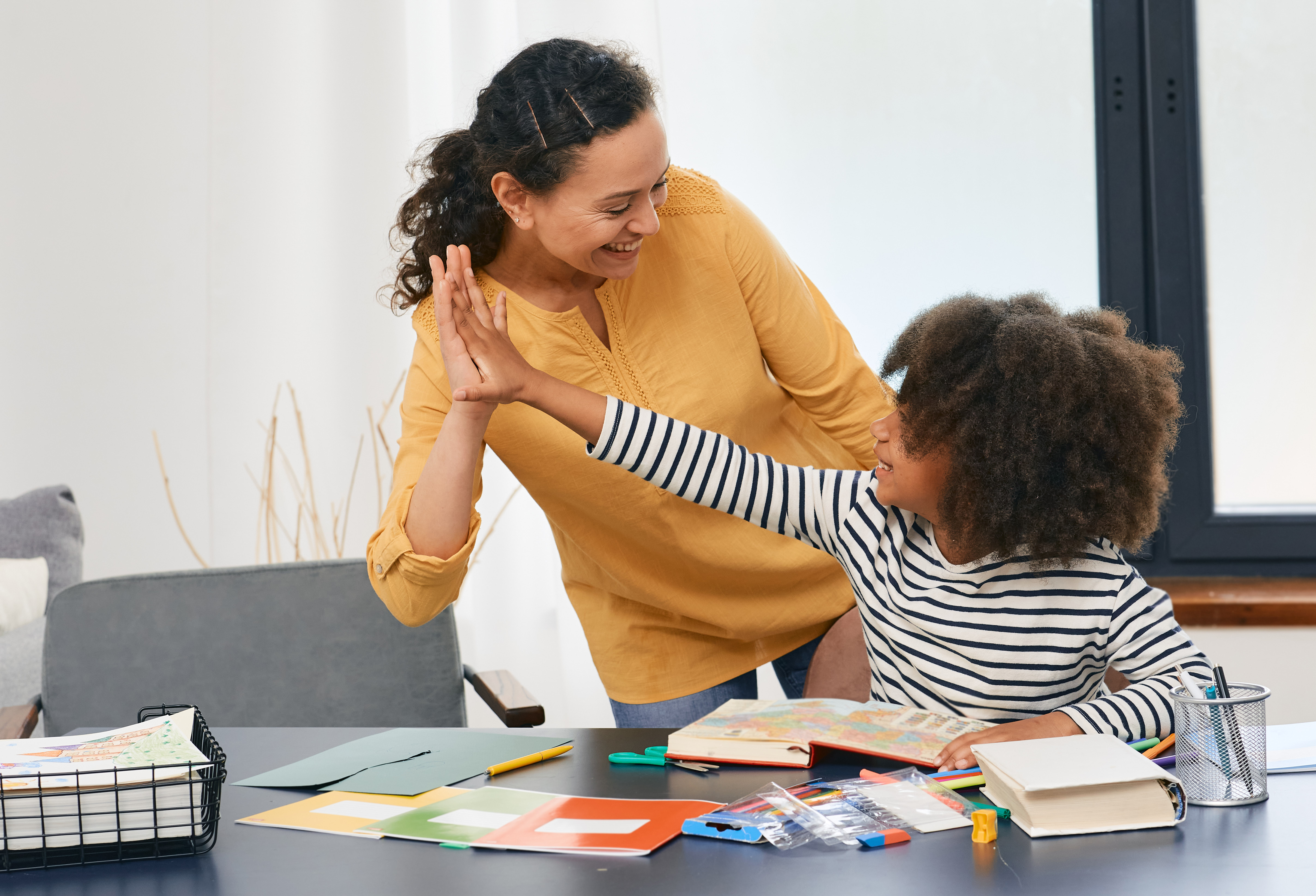 Girl high fives adult while doing homework.