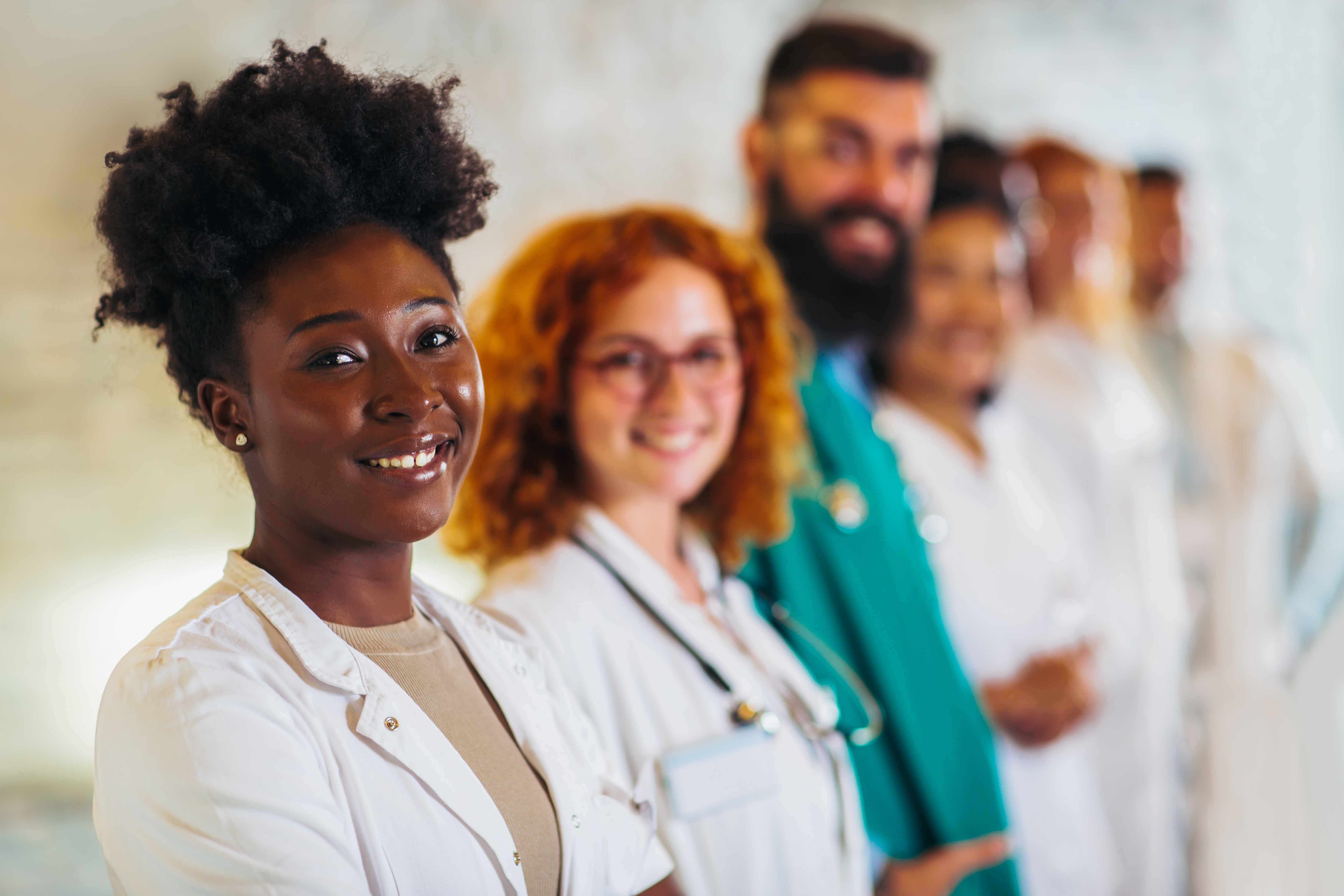 Various healthcare professionals stand in line smiling.