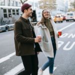 couple walking on street with coffee cups