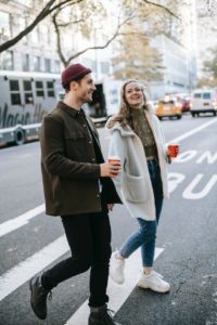 couple walking on street with coffee cups