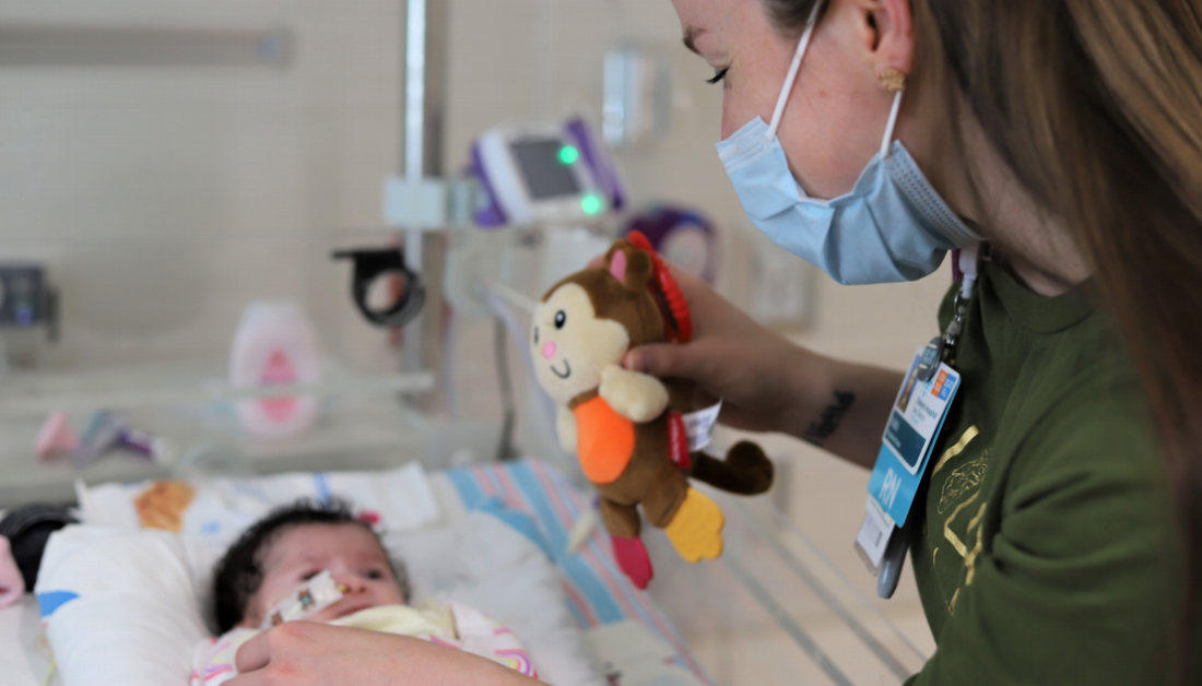 Sara Lass uses toy monkey to play with baby in Children’s Hospital Cardiac Intensive Care Unit.