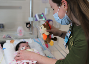 Sara Lass uses toy monkey to play with baby in Children’s Hospital Cardiac Intensive Care Unit.