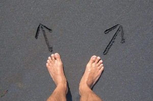 Person standing barefoot on black sand beach