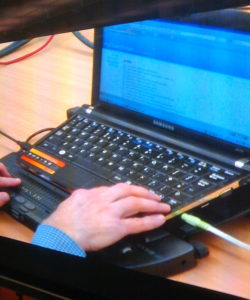 White person's hand using a computer with blue faint screen equipped with JAWS screen reader