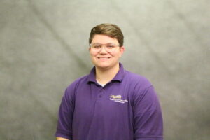 Brown-haired individual in LSU Purple polo shirt, smiling
