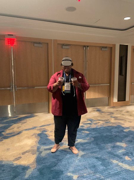 Jakeel wears VR headset smiling while holding the VR handsets up to his chest.