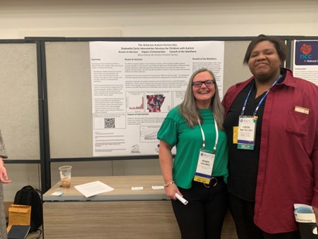 Jakeels stands next to Renee Holmes as they smile in front of her research poster.