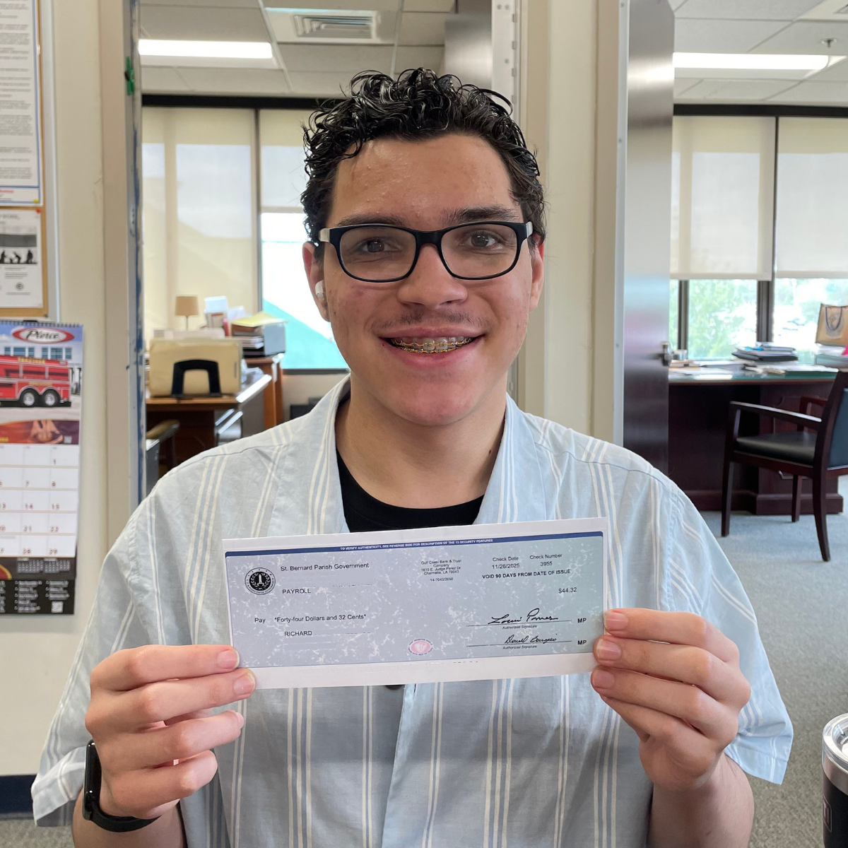PAYCheck student in office holding paycheck.